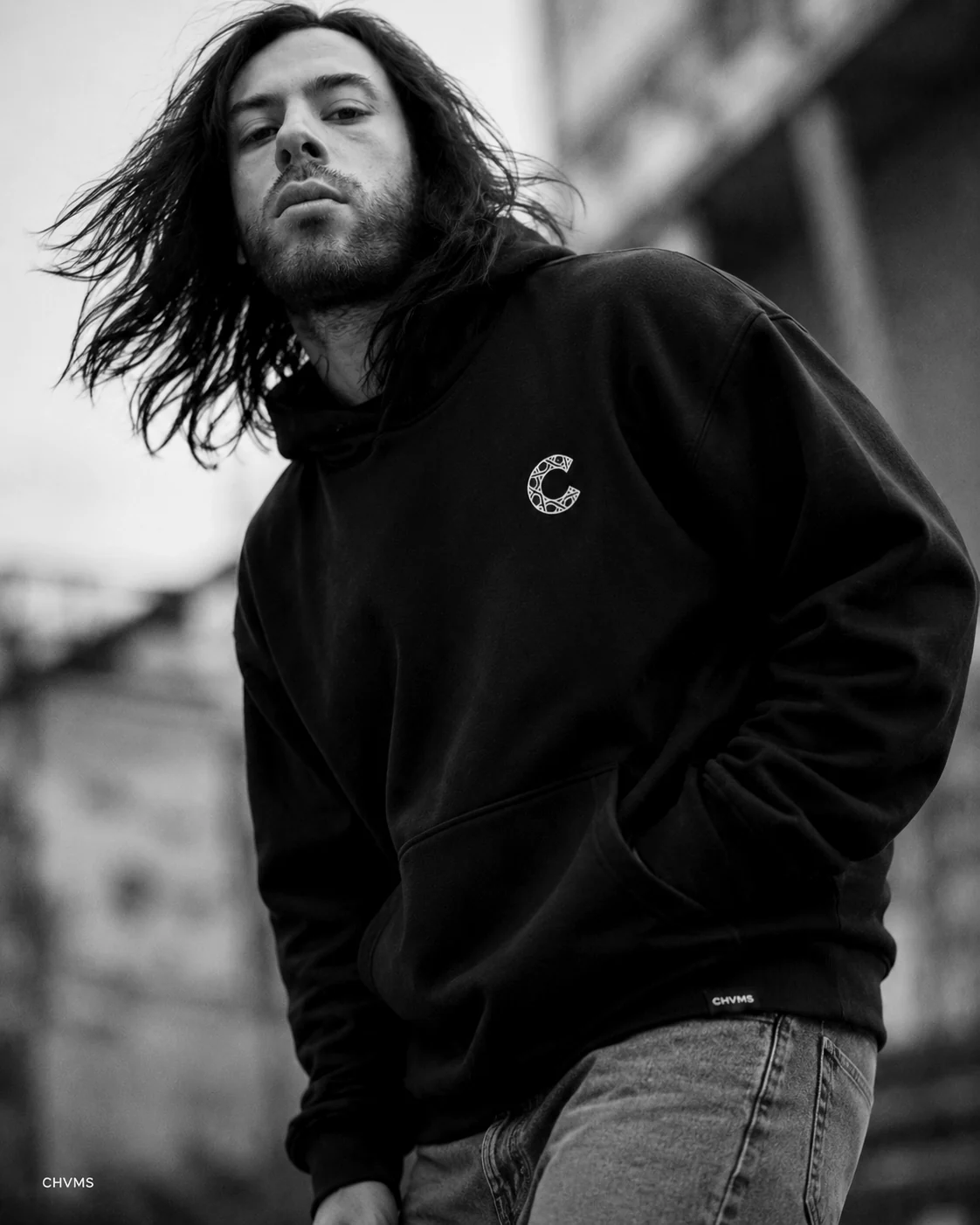 Hoodie noir CHVMS porté en extérieur, monogramme brodé sur la poitrine